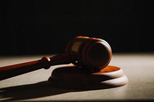 Justice and law concept.Male judge in a courtroom with the gavel, working with, computer and docking keyboard, eyeglasses, on table in morning light photo