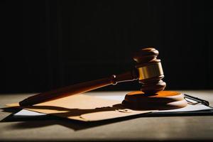 Justice and law concept.Male judge in a courtroom with the gavel, working with, computer and docking keyboard, eyeglasses, on table in morning light photo