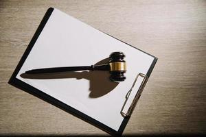 Justice and law concept.Male judge in a courtroom with the gavel, working with, computer and docking keyboard, eyeglasses, on table in morning light photo