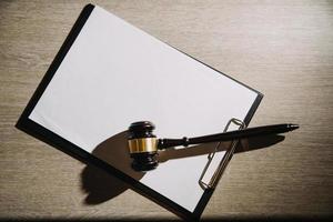 Justice and law concept.Male judge in a courtroom with the gavel, working with, computer and docking keyboard, eyeglasses, on table in morning light photo