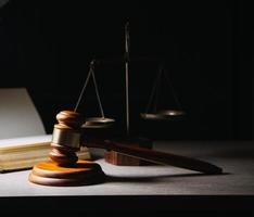 Justice and law concept.Male judge in a courtroom with the gavel, working with, computer and docking keyboard, eyeglasses, on table in morning light photo