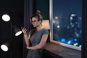 Businesswoman using wireless earbuds and smartphone during late night work photo