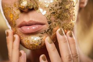 hermosa mujer con máscara dorada brillante en la cara para el tratamiento de la piel foto