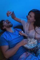 pareja joven y feliz comiendo palomitas de maíz y viendo películas foto