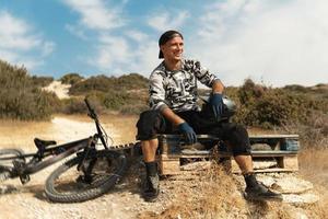 Bike rider relaxing after downhill race on bicycle in a mountains photo