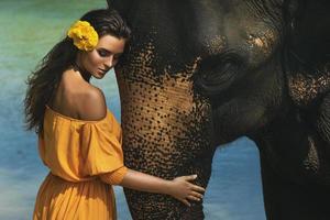 mujer con hermoso vestido naranja y poderoso elefante foto