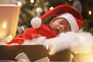 lindo bebé recién nacido con sombrero de santa claus está durmiendo en la caja de regalo de navidad