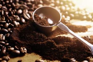 Closeup of steel spoon, grounded coffee and beans photo