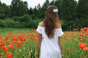 bella mujer en el campo con muchas flores de amapola foto