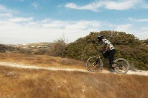 Professional bike rider during downhill ride on his bicycle in mountains photo