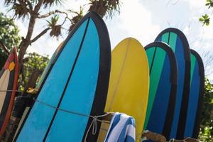 pila de diferentes tablas de surf para alquilar en la playa foto