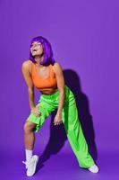 bailarina despreocupada que usa ropa deportiva colorida divirtiéndose contra el fondo púrpura foto