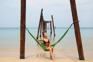 Woman is relaxing in the hammock hanging on old beams from the broken pier photo