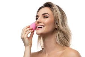 Beautiful woman with a smooth skin holding makeup sponge on white background photo