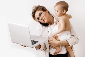 joven y ocupada mujer de negocios está trabajando y sosteniendo a su pequeño bebé foto