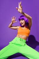 Bailarina despreocupada con ropa deportiva colorida actuando contra un fondo morado foto
