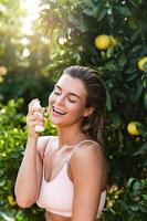 Joyful and beautiful woman applying moisturizing cream or sunblock on her facial skin photo