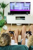Two girls playing video game console in living room photo