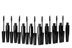 Black mascara brushes and containers on white background photo