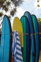 pila de diferentes tablas de surf para alquilar en la playa foto