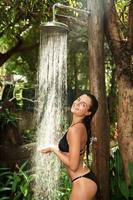 Beautiful woman taking outdoor shower in the tropical jungle photo