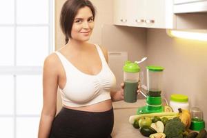 Pregnant woman holding shaker with a green protein cocktail photo