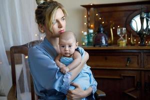 Young beautiful mother with her cute little baby wrapped in the blue cloth photo