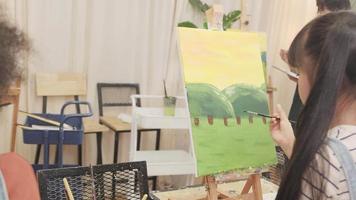 une fille asiatique se concentre sur la peinture acrylique couleur sur toile avec des enfants multiraciaux dans une classe d'art, l'apprentissage créatif avec des talents et des compétences dans l'enseignement en studio de l'école primaire. video