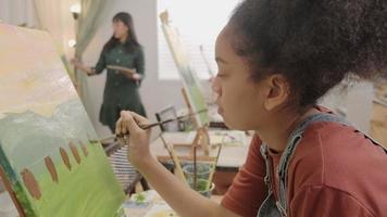 une fille noire se concentre sur la peinture acrylique couleur sur toile avec des enfants multiraciaux dans une classe d'art, l'apprentissage créatif avec des talents et des compétences dans l'enseignement en studio de l'école primaire.