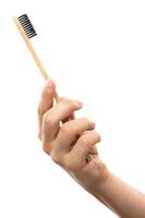mano femenina con un cepillo de dientes de bambú ecológico foto