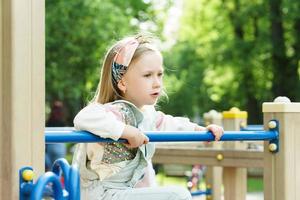 Cute little girl playing on a playground in a city park photo