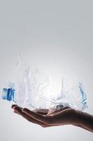 Hand with used plastic bottle and dispersion effect. Concept of plastic recycling. photo