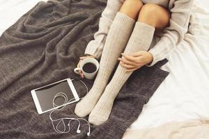 Woman wearing warm woolen stockings is drinking hot coffee at cold winter day photo