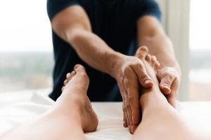 Masseur man during female foot massage photo