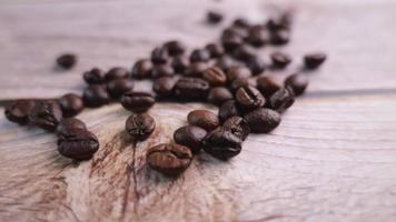 close-up video of coffee beans being poured onto a wooden floor, moving slowly in focus at some point. Provides a warm glow with a warm mood infused with a slight darkness in studio photography.