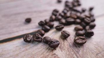 close-up video of coffee beans being poured onto a wooden floor, moving slowly in focus at some point. Provides a warm glow with a warm mood infused with a slight darkness in studio photography.