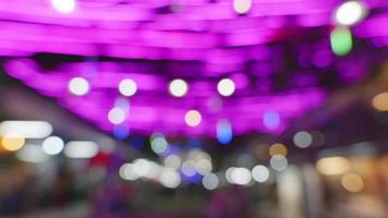 sfondo sfocato nel mercato notturno, la luce delle lampade crea un bokeh zonale. da bulbo rosa video