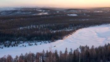 The rays of the setting sun illuminate the frozen river. The car drives along the frozen river. Chulman river in winter in Neryungri. South Yakutia, Russia video