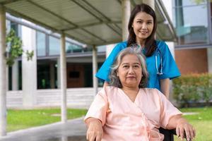 Asian careful caregiver or nurse taking care of the patient in a wheelchair.  Concept of happy retirement with care from a caregiver and Savings and senior health insurance, a Happy family photo