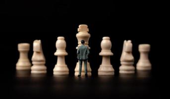 Figures businessman standing in front of wooden chess on black isolated background. Concept of business analysis and strategy. Stepping into the startup, new business player photo