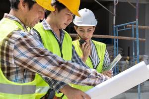 ingeniera asiática o arquitecta joven se puso un casco por seguridad y habló con un contratista en un proyecto de construcción de fábrica, concepto de trabajo en equipo, concepto de liderazgo. foto