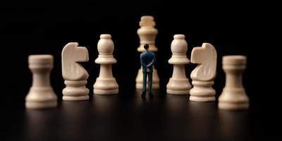 Figures businessman standing in front of wooden chess on black isolated background. Concept of business analysis and strategy. Stepping into the startup, new business player photo