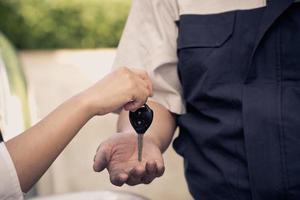 el primer plano de la mano de la mujer está enviando las llaves del auto al mecánico del auto. el concepto de confianza y confianza en el uso del servicio foto