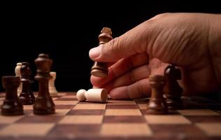 Close up of hands confident businessman moving chess figure in competition success play. the chess game is development analysis, strategy, and plan, the management or leadership concept. photo
