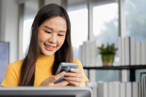 Portrait happy young programmer Asian woman work at start up technology office and using smartphone and testing mobile application and excited in success. Concept of smart entrepreneur woman working. photo