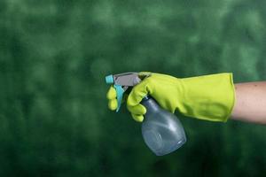 hand with protective glove holding packaging of cleaning products used for home hygiene photo