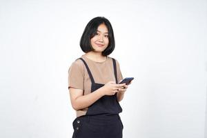 usando un smartphone y sonriendo a una hermosa mujer asiática aislada de fondo blanco foto
