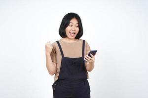 usando un teléfono inteligente con un gesto de celebración del sí de una hermosa mujer asiática aislada de fondo blanco foto