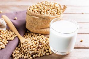 Soy milk in a glass with soybeans on a wooden table Organic breakfast, high protein, healthy, agricultural products, vegetarian photo