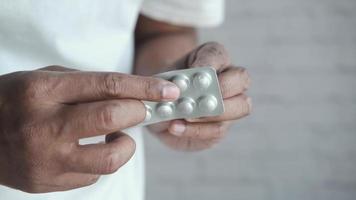 Adult popping a pill from a foil pill pack video